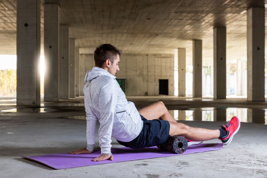 man foam rolling under bridge